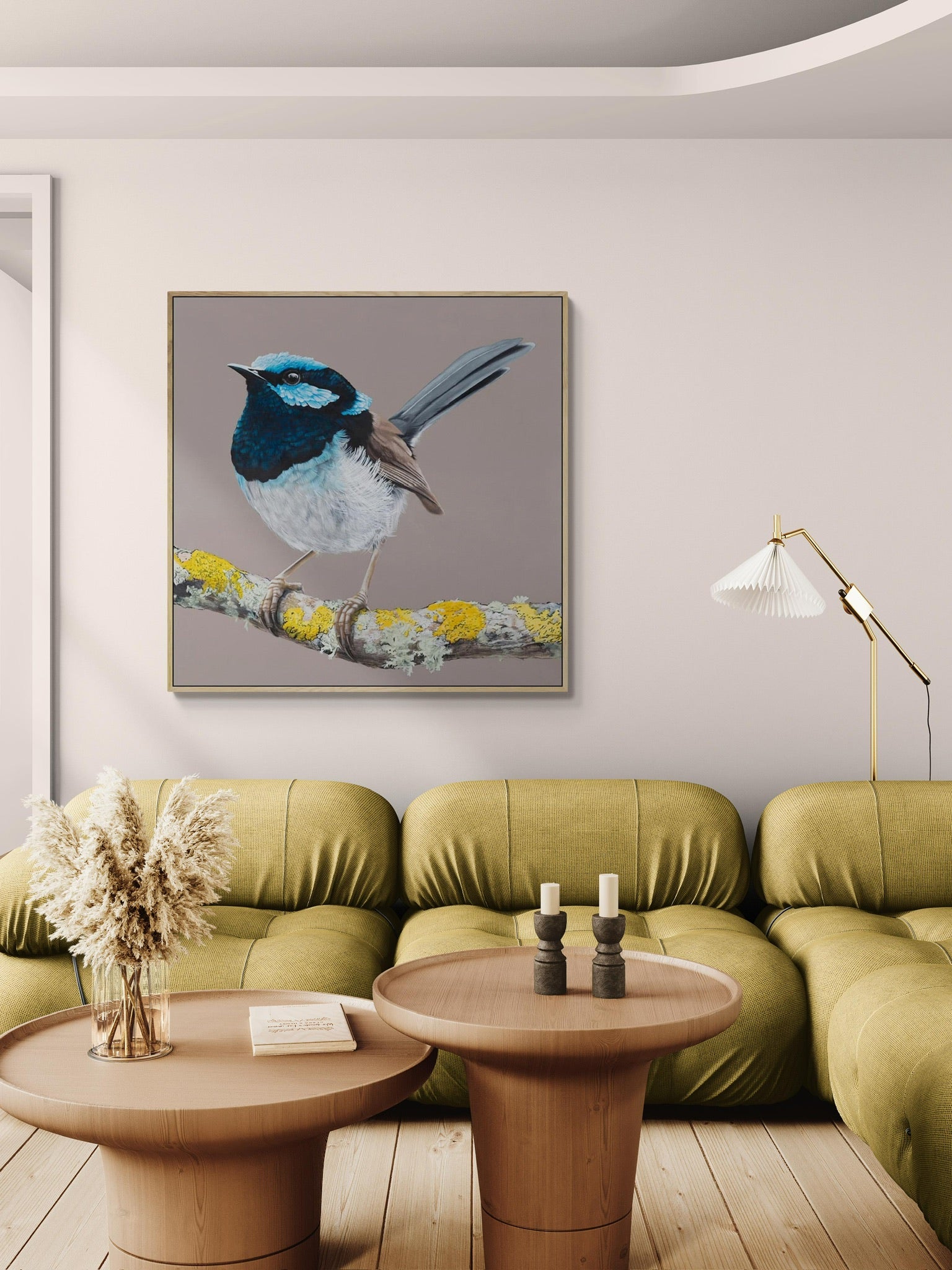 A framed print of a Blue Wren ( male superb fairy-wren) perched on a branch, displayed on a wall above a green sofa and wooden coffee table. Australian Bird Art Prints — Limited Edition | Geoffrey Carran 