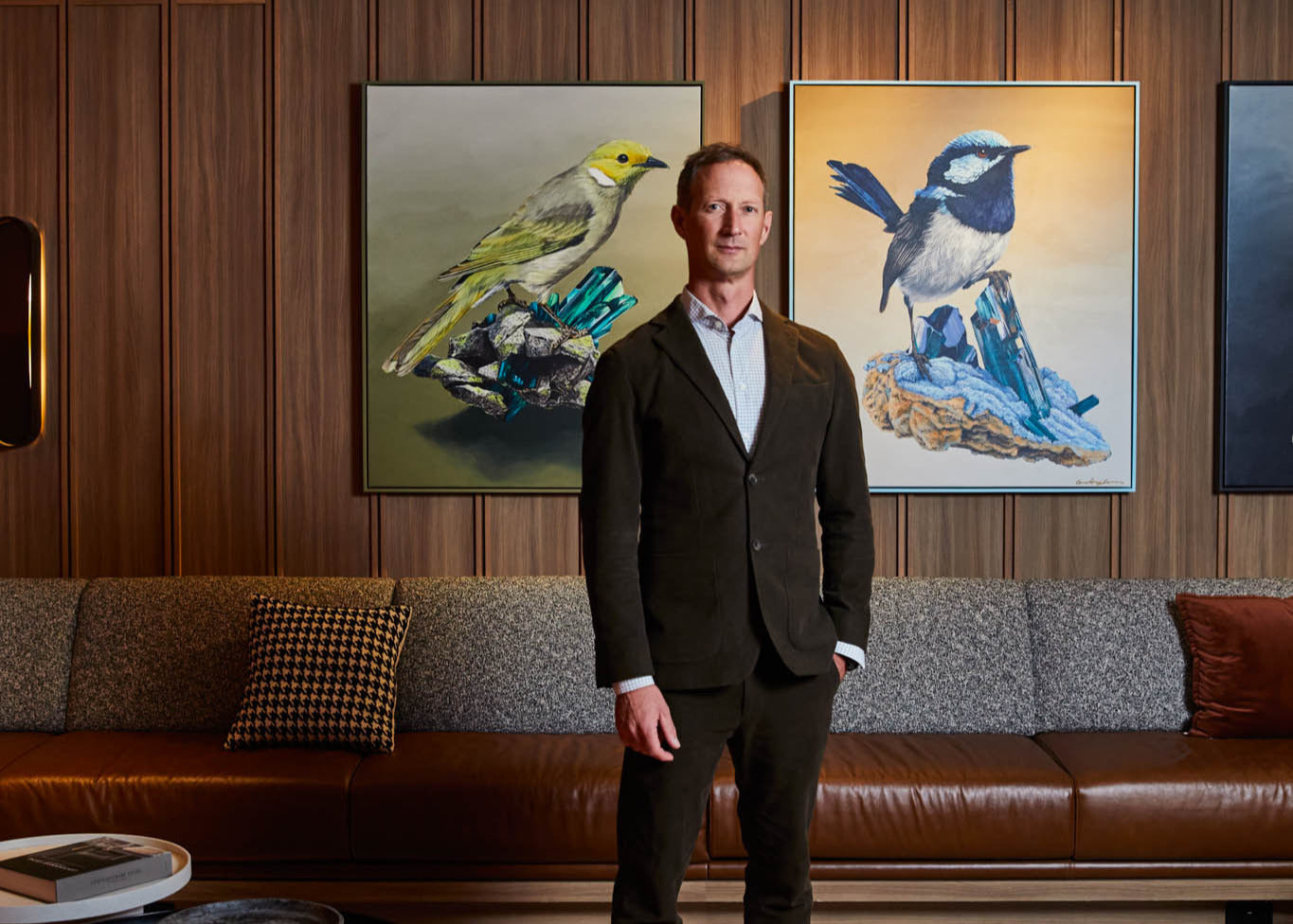 Geoffrey Carran standing infront of his paintings
